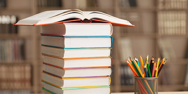 Bücherstapel mit aufgeschlagenem Buch